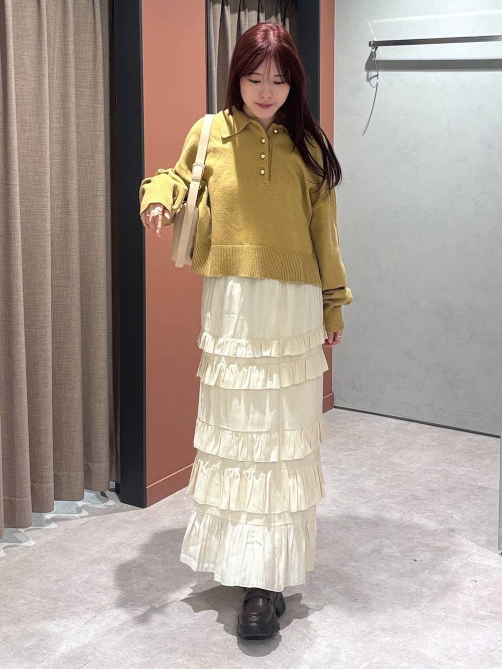 ベージュ系のショルダーバッグ、ブラック系のローファー、ホワイト系のスカートを着用したレディースの冬コーディネートの2枚目の写真