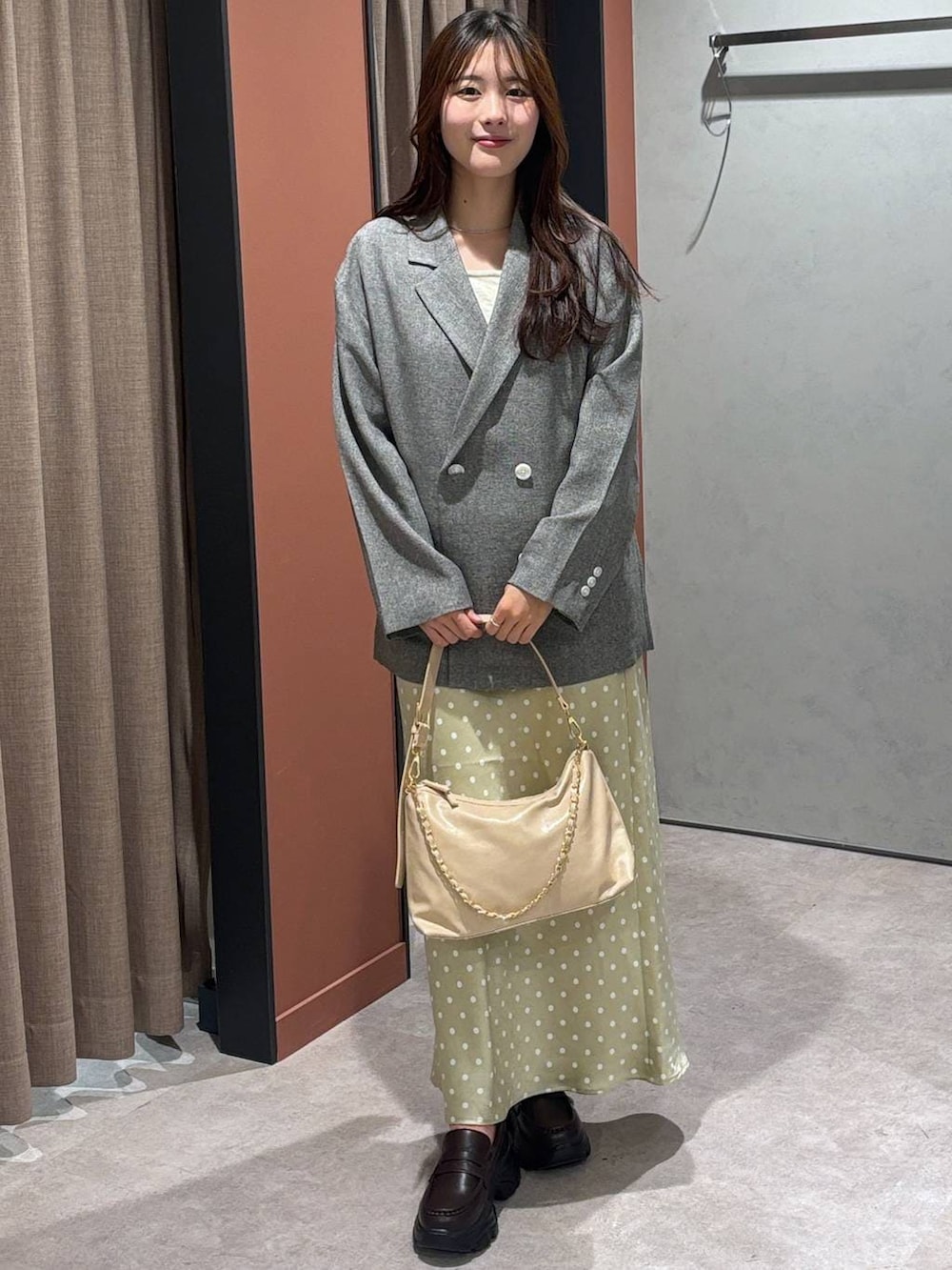 ベージュ系のスカート、グレー系のテーラードジャケット、ベージュ系のショルダーバッグを着用したレディースの冬コーディネートの4枚目の写真