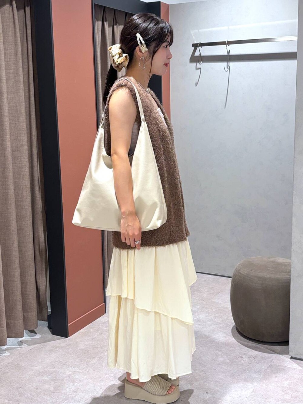 ホワイト系のショルダーバッグ、ホワイト系のサンダル、ブラウン系のベストを着用したレディースの夏コーディネートの2枚目の写真