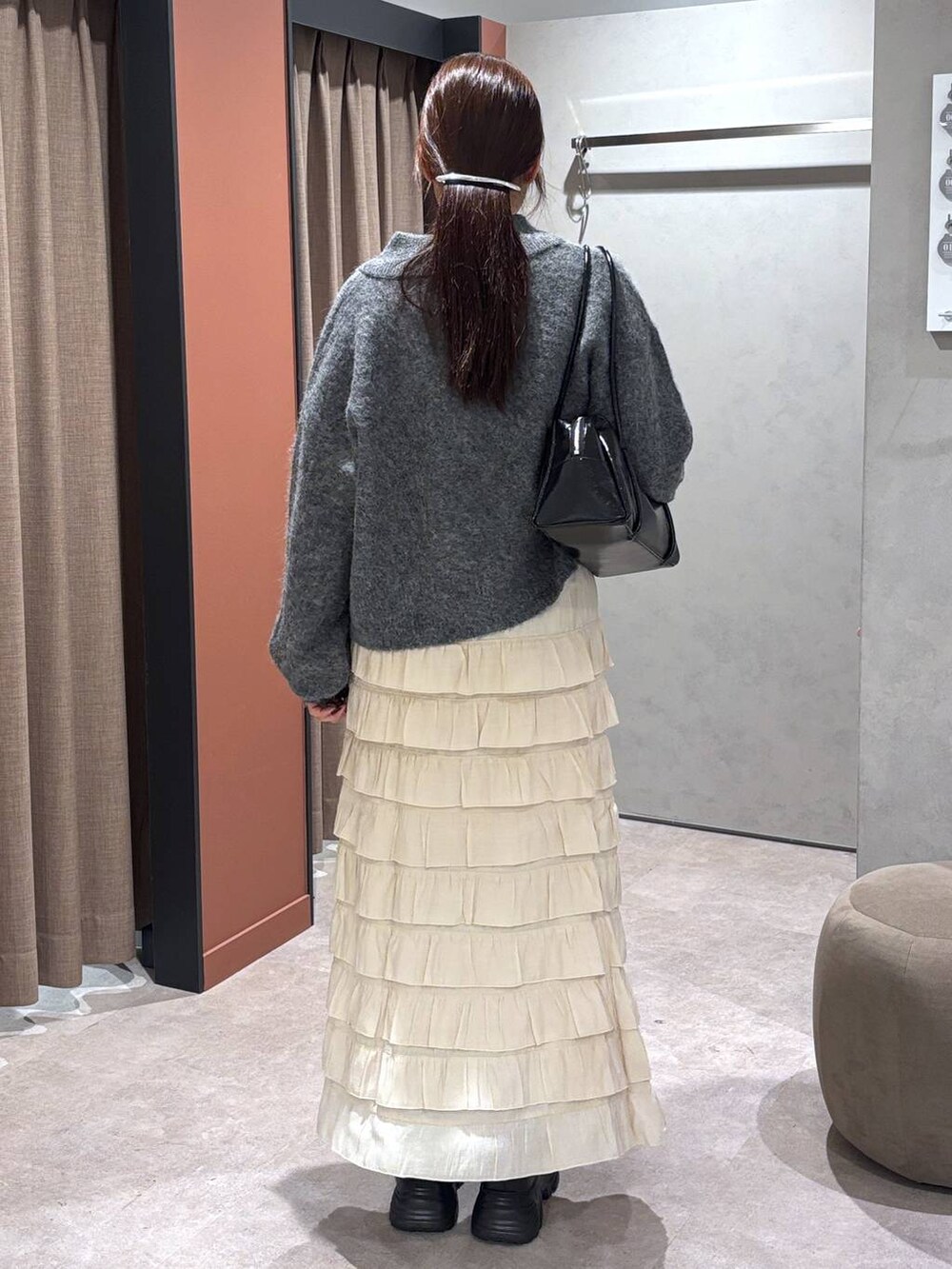 ブラック系のブーツ、ホワイト系のスカート、グレー系のニット/セーターを着用したレディースの秋コーディネートの3枚目の写真