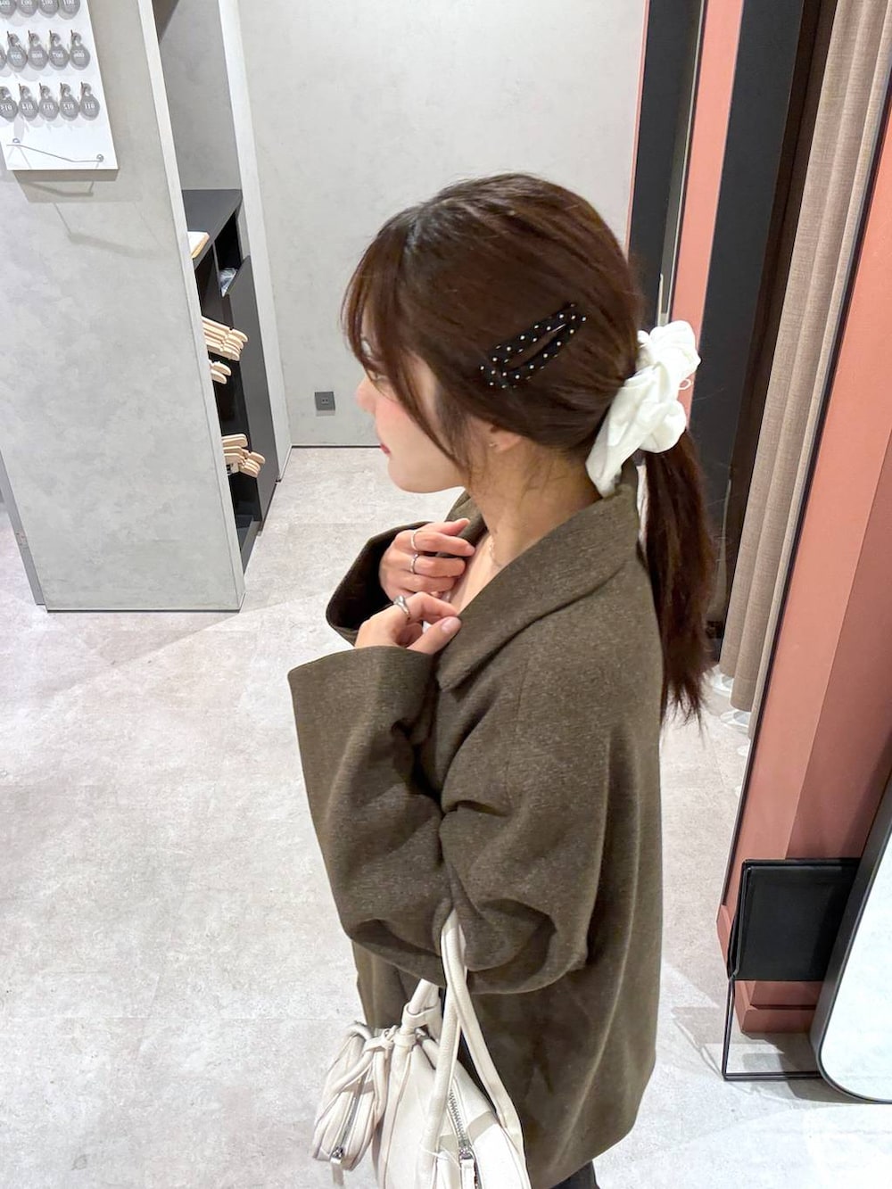 ブラウン系のその他アウター、ホワイト系のボストンバッグを着用したレディースの冬コーディネートの2枚目の写真