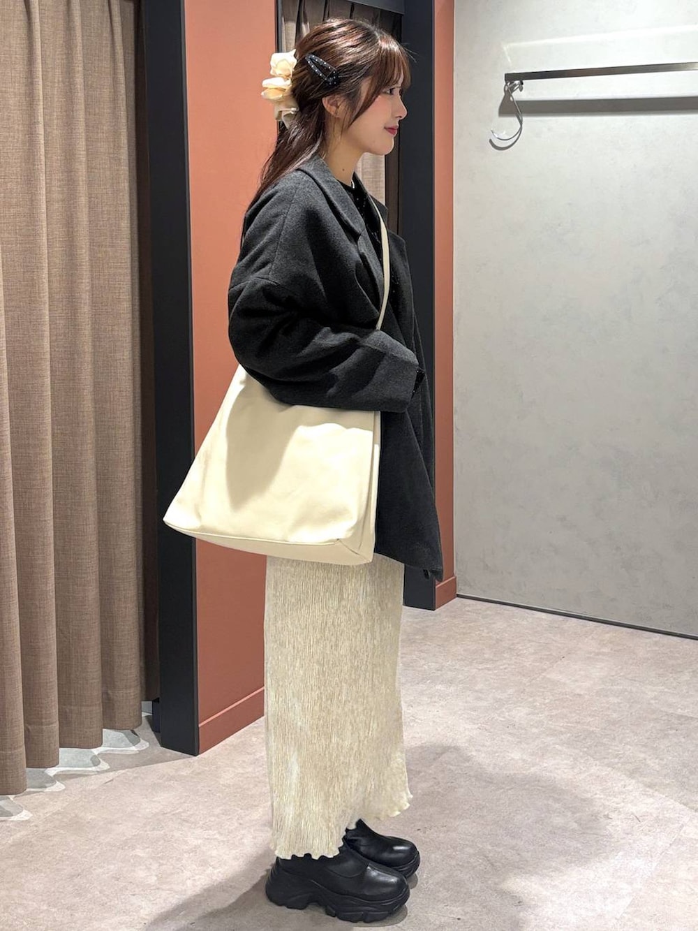 ブラック系のショルダーバッグ、ブラック系のブーツ、ホワイト系のスカートを着用したレディースの冬コーディネートの2枚目の写真