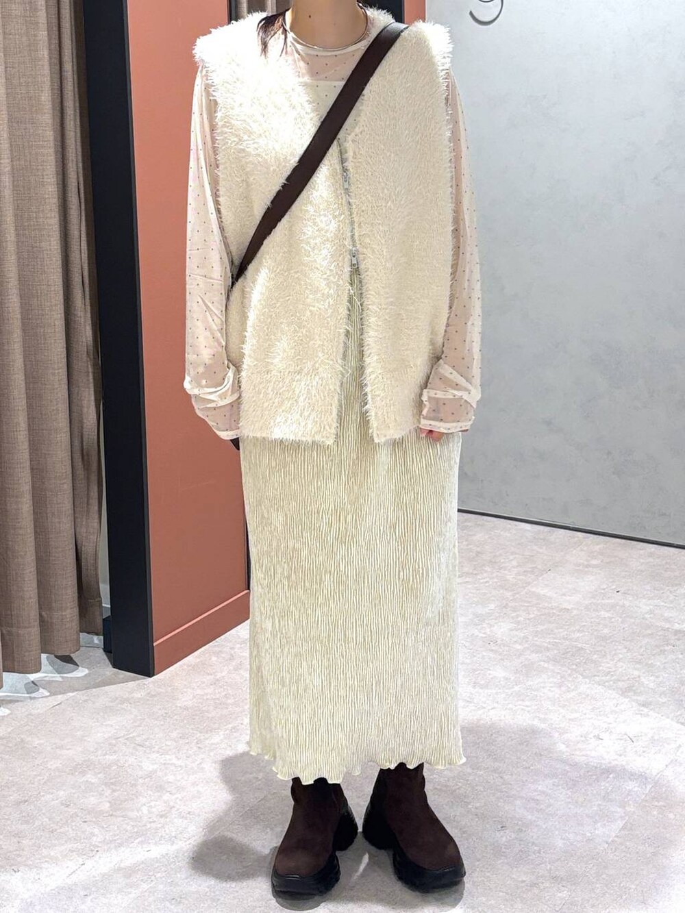 ホワイト系のベスト、ブラウン系のショルダーバッグ、ホワイト系のスカートを着用したレディースの秋コーディネートの4枚目の写真