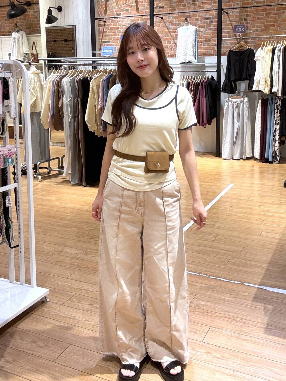 オレンジ系のデニムパンツ、ブラック系のサンダル、イエロー系のベルトを着用したレディースの春コーディネートの4枚目の写真