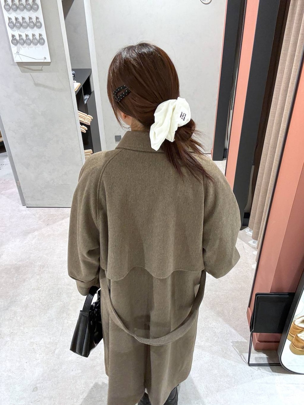 グレー系のスカート、ブラウン系のステンカラーコート、ブラック系のショルダーバッグを着用したレディースの冬コーディネートの3枚目の写真