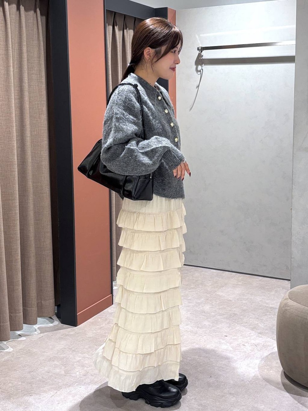 ブラック系のブーツ、ホワイト系のスカート、グレー系のニット/セーターを着用したレディースの秋コーディネートの2枚目の写真