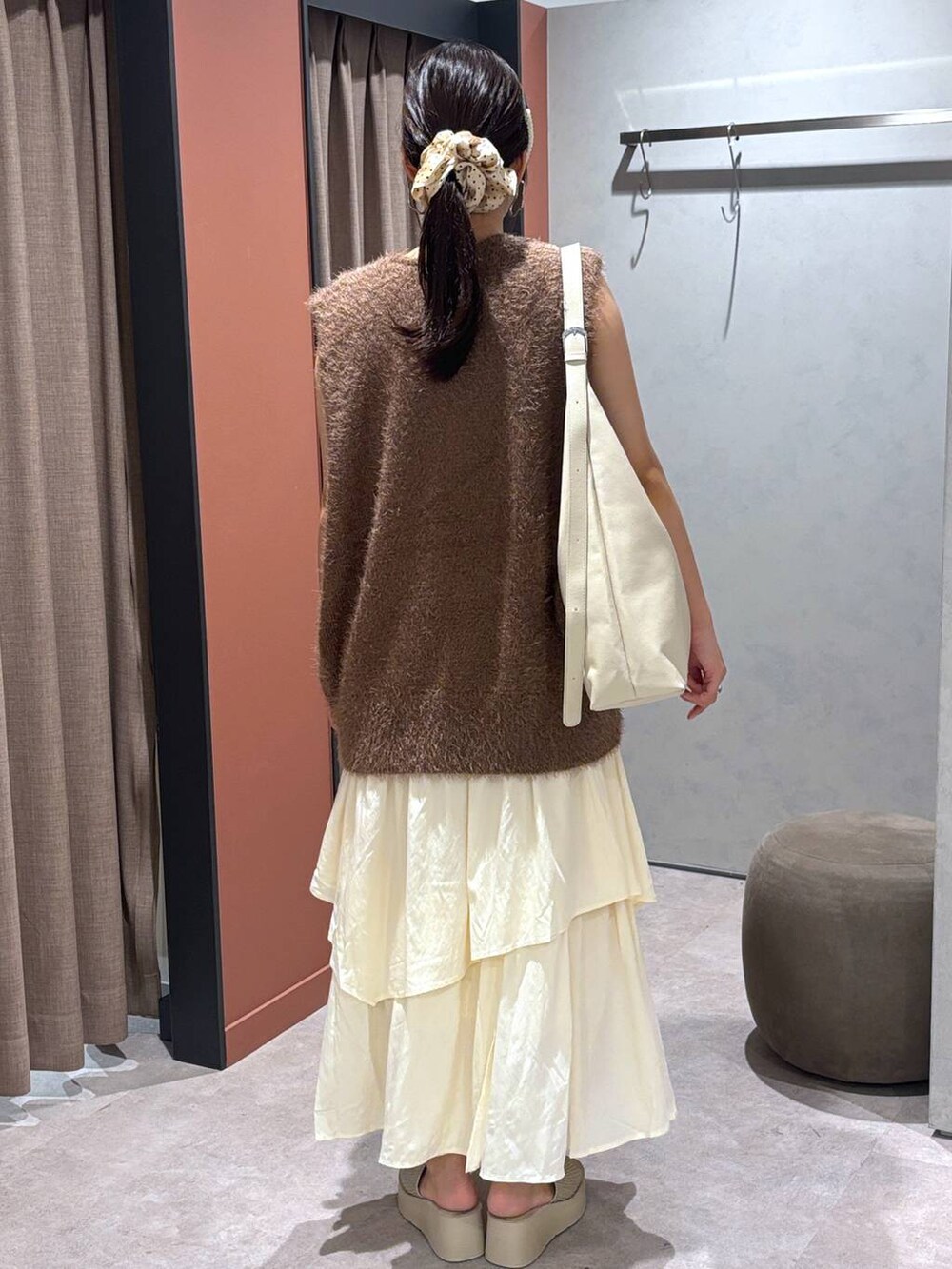 ホワイト系のショルダーバッグ、ホワイト系のサンダル、ブラウン系のベストを着用したレディースの夏コーディネートの3枚目の写真