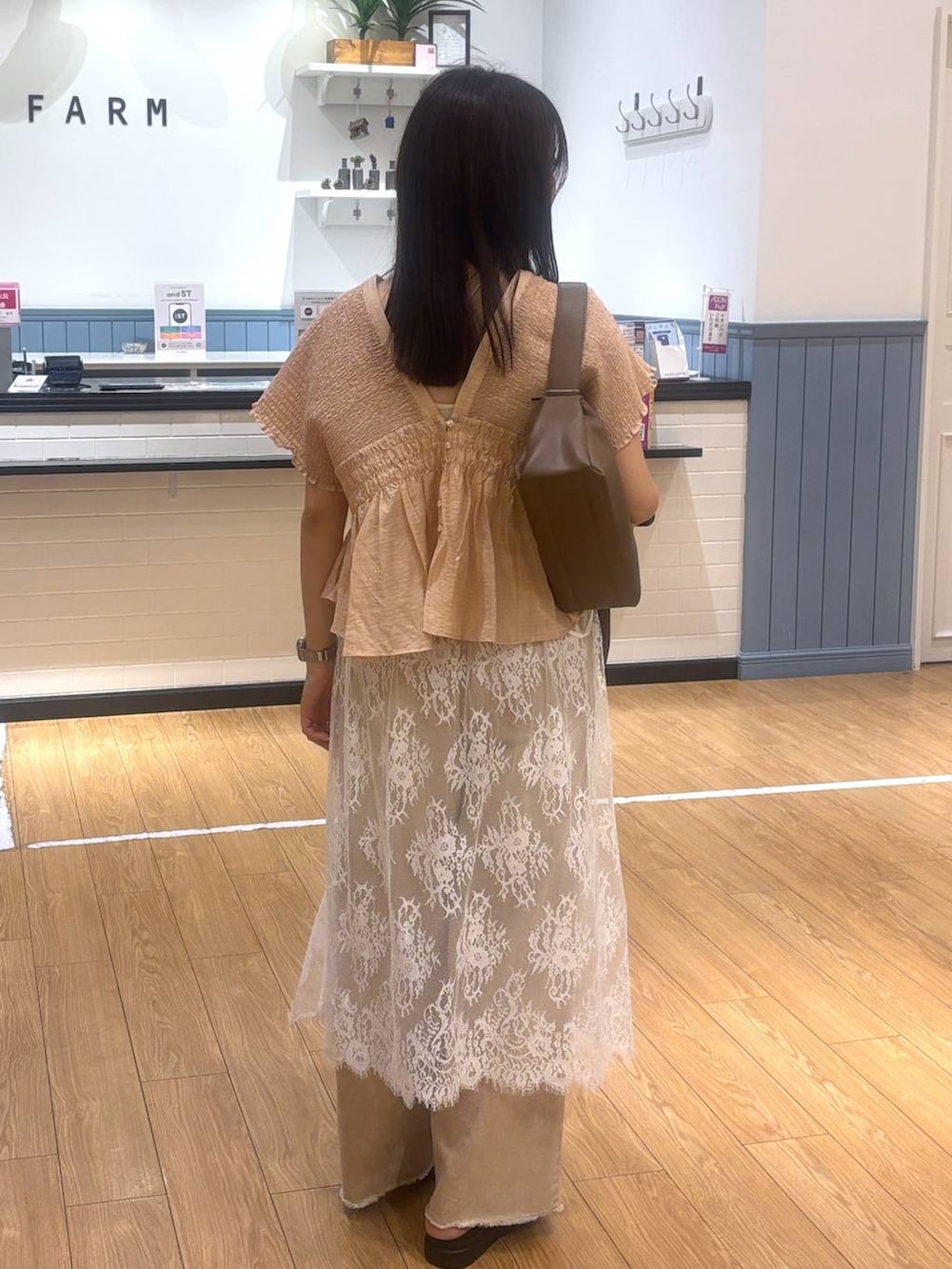 オレンジ系のデニムパンツ、ブラウン系のサンダル、ブラウン系のショルダーバッグを着用したレディースの春コーディネートの3枚目の写真