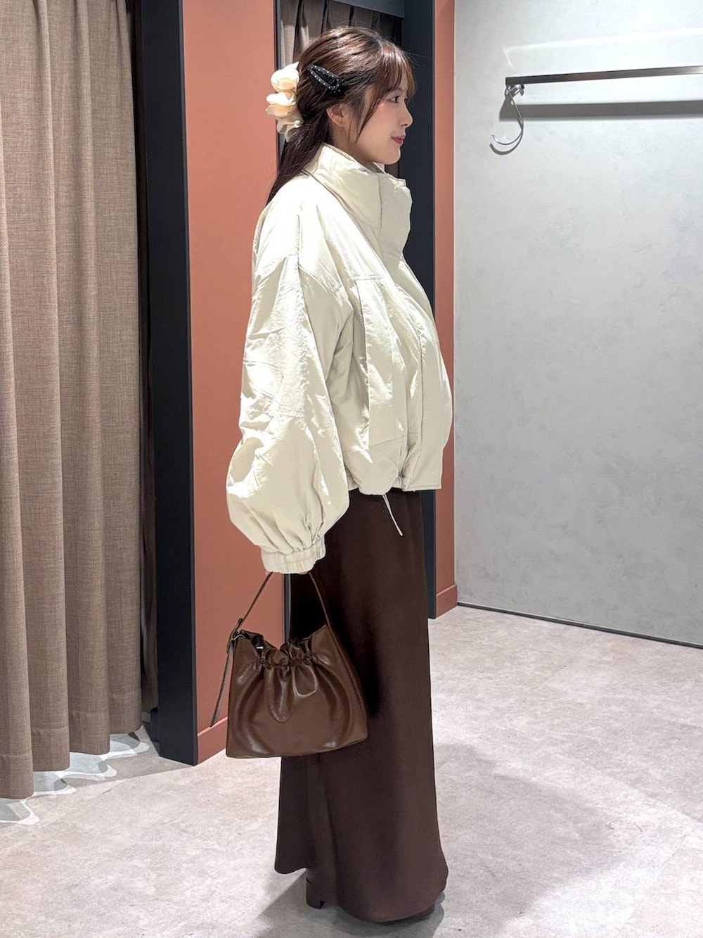 ホワイト系のその他アウター、ブラウン系のスカート、ブラウン系のショルダーバッグを着用したレディースの冬コーディネートの2枚目の写真