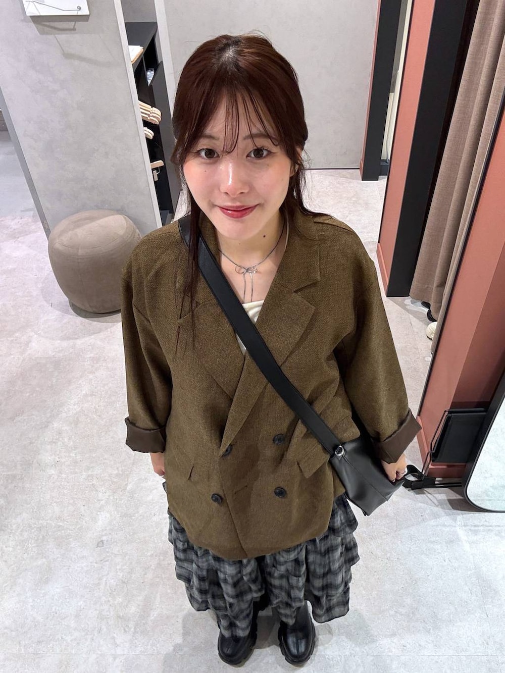 ブラック系のブーツ、ベージュ系のテーラードジャケット、ホワイト系のキャミソールを着用したレディースの秋コーディネートの2枚目の写真