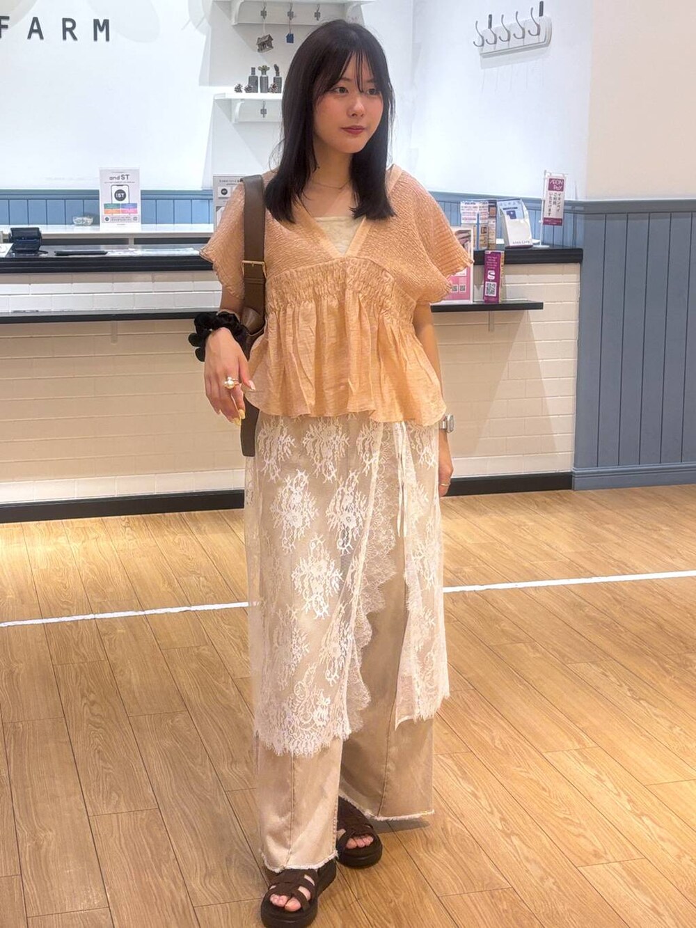 オレンジ系のデニムパンツ、ブラウン系のサンダル、ブラウン系のショルダーバッグを着用したレディースの春コーディネートの4枚目の写真