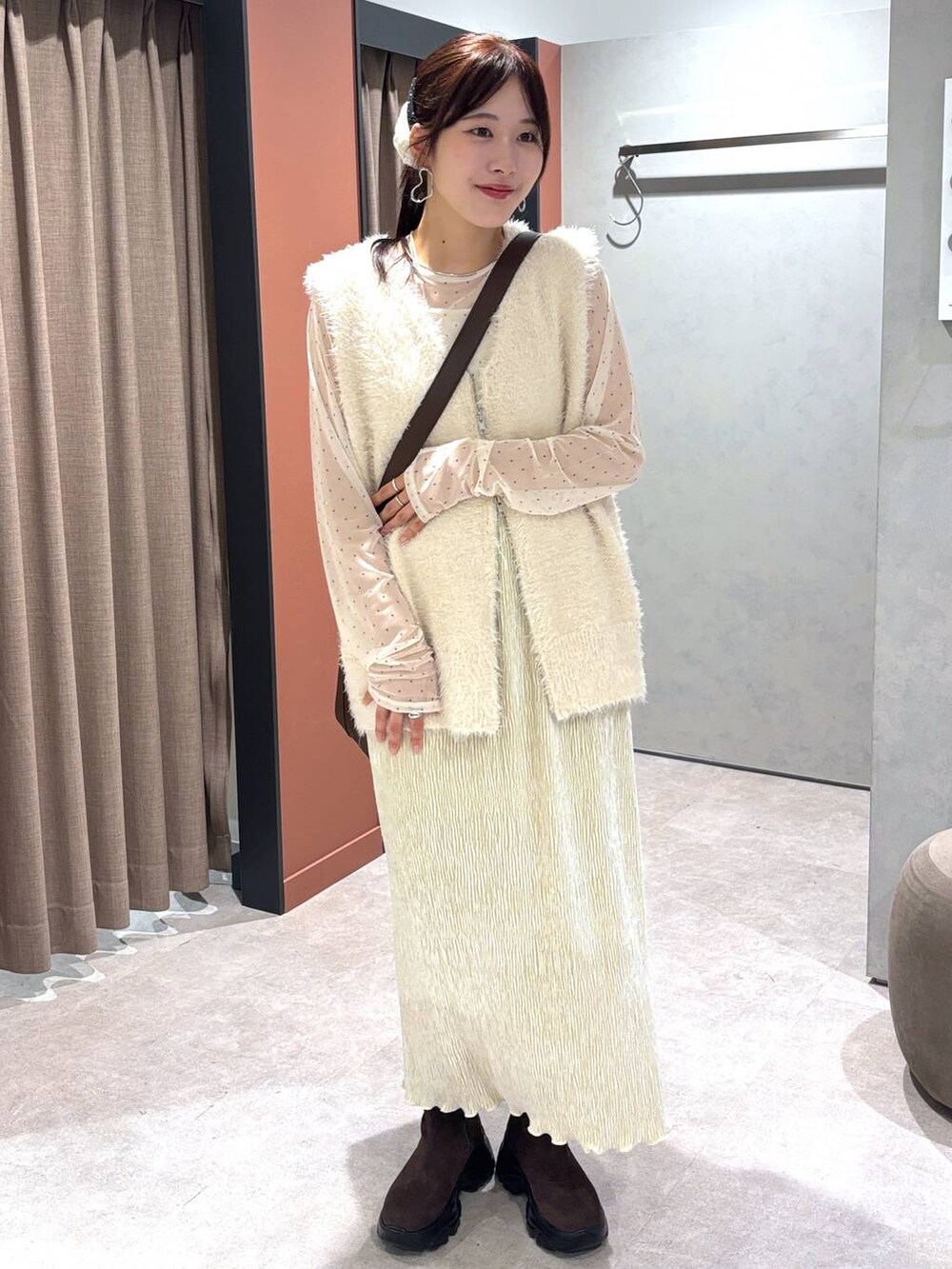 ホワイト系のベスト、ブラウン系のショルダーバッグ、ホワイト系のスカートを着用したレディースの秋コーディネートの5枚目の写真