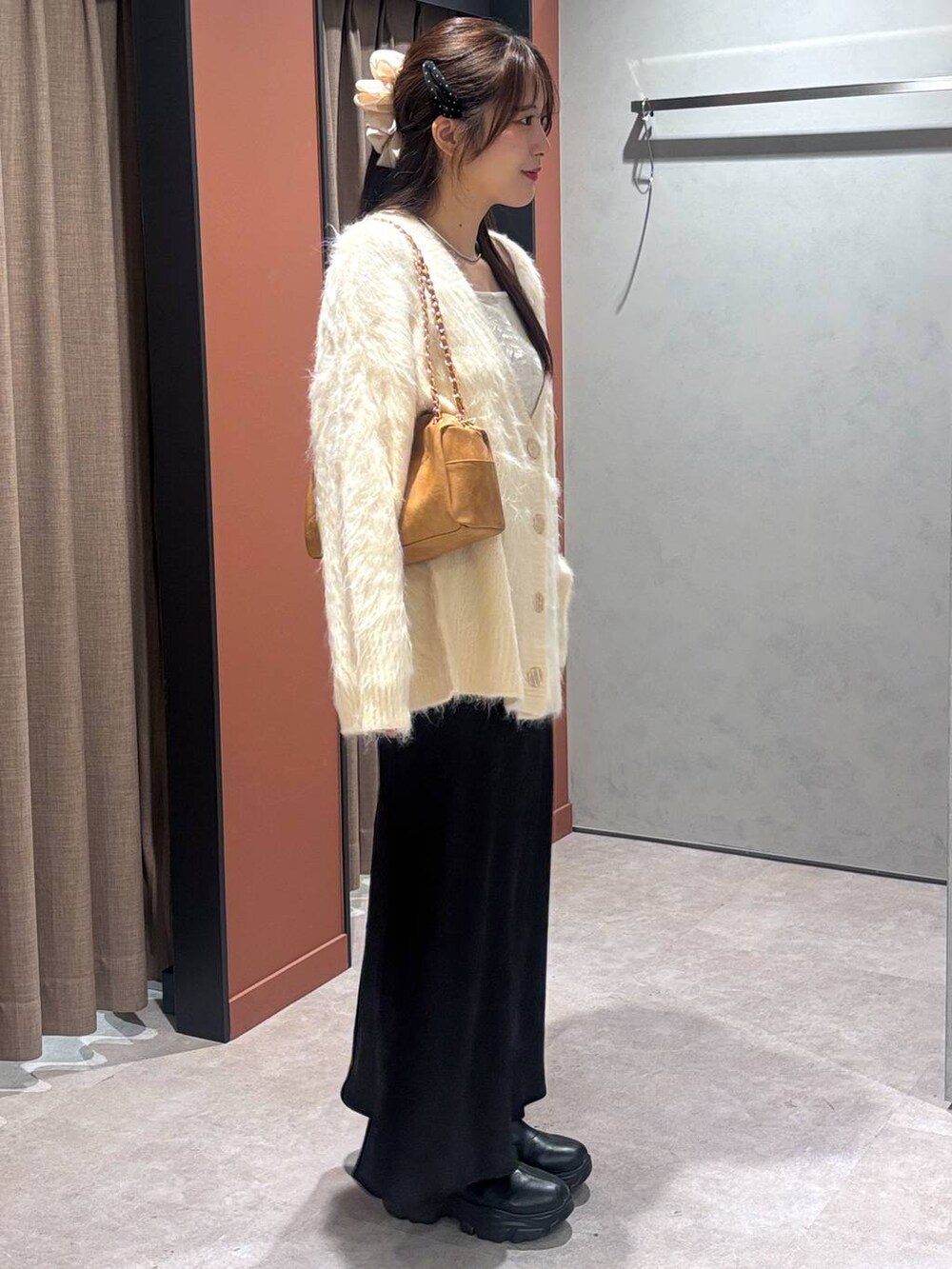 ブラック系のブーツ、ブラック系のスカート、ホワイト系のカーディガン/ボレロを着用したレディースの秋コーディネートの2枚目の写真