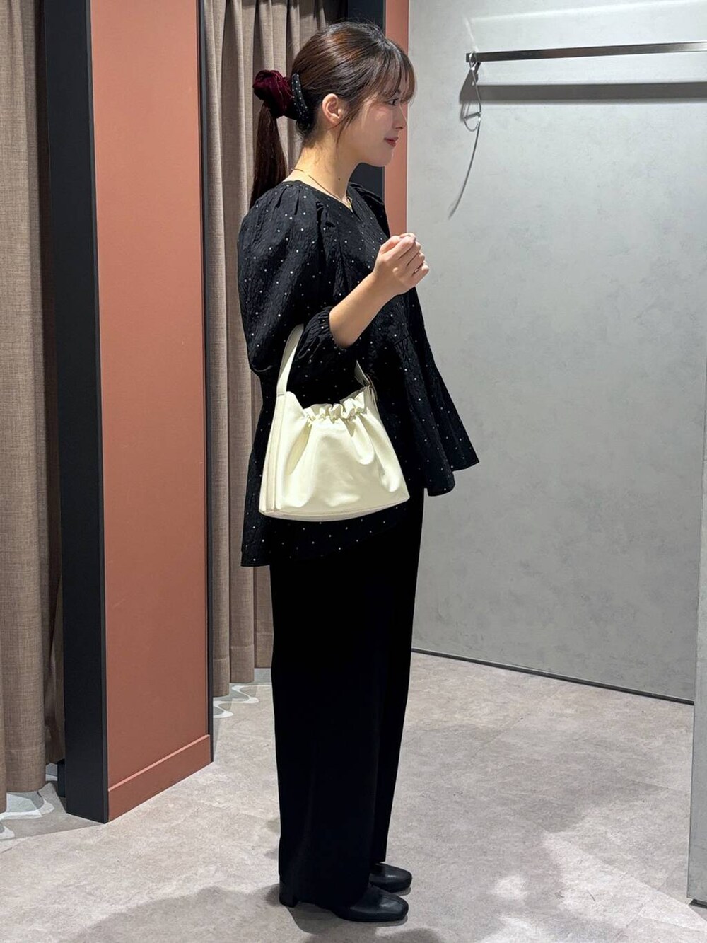 ブラック系のブーツ、ホワイト系のショルダーバッグ、ブラック系のスラックスを着用したレディースの冬コーディネートの2枚目の写真