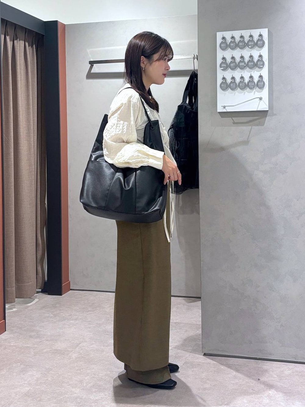 ブラウン系のスラックス、ブラウン系のスカート、ブラック系のトートバッグを着用したレディースの春コーディネートの2枚目の写真