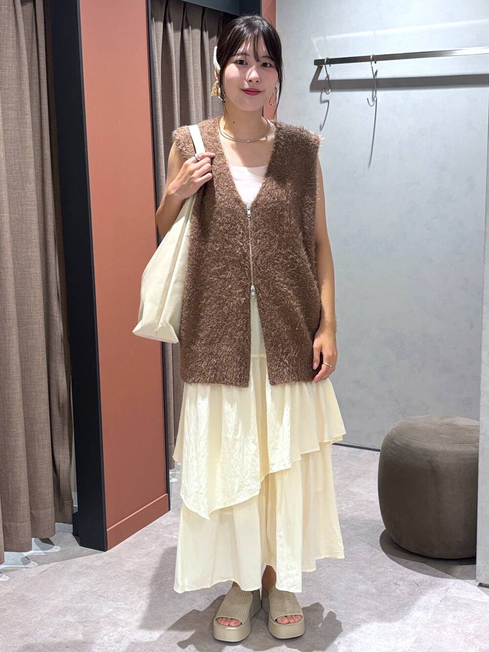 ホワイト系のショルダーバッグ、ホワイト系のサンダル、ブラウン系のベストを着用したレディースの夏コーディネートの4枚目の写真