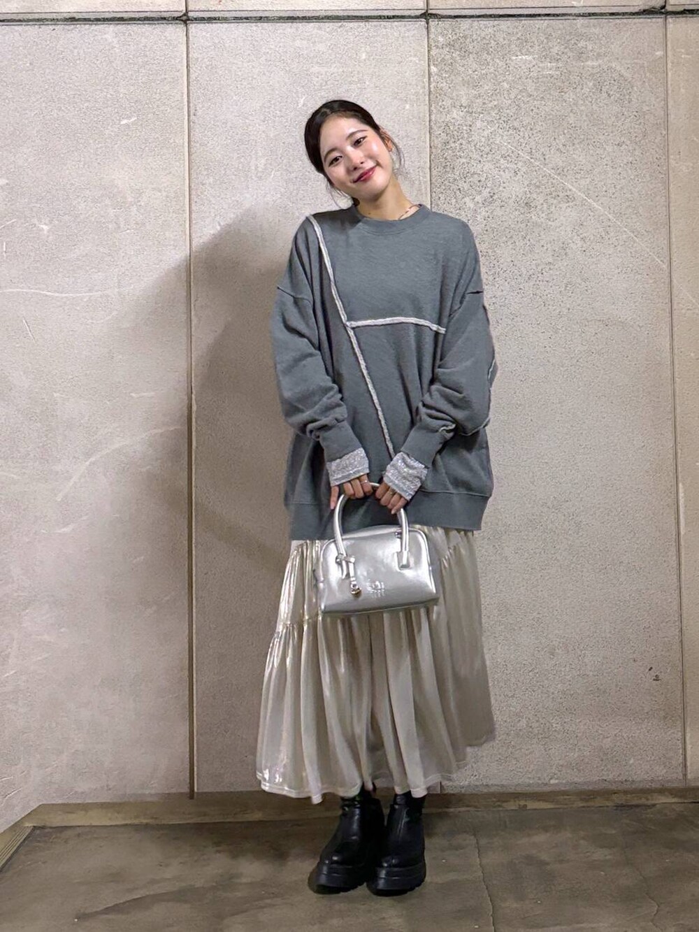 ブラック系のブーツ、ホワイト系のスカート、シルバー系のTシャツ/カットソーを着用したレディースの秋コーディネートの2枚目の写真
