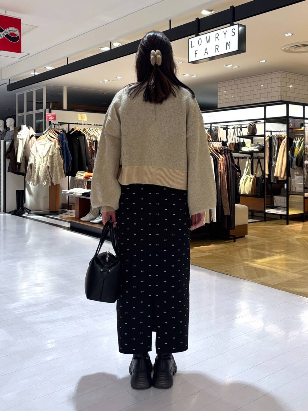 ブラック系のスカート、ブラック系のブーツ、ブラック系のショルダーバッグを着用したレディースの冬コーディネートの3枚目の写真