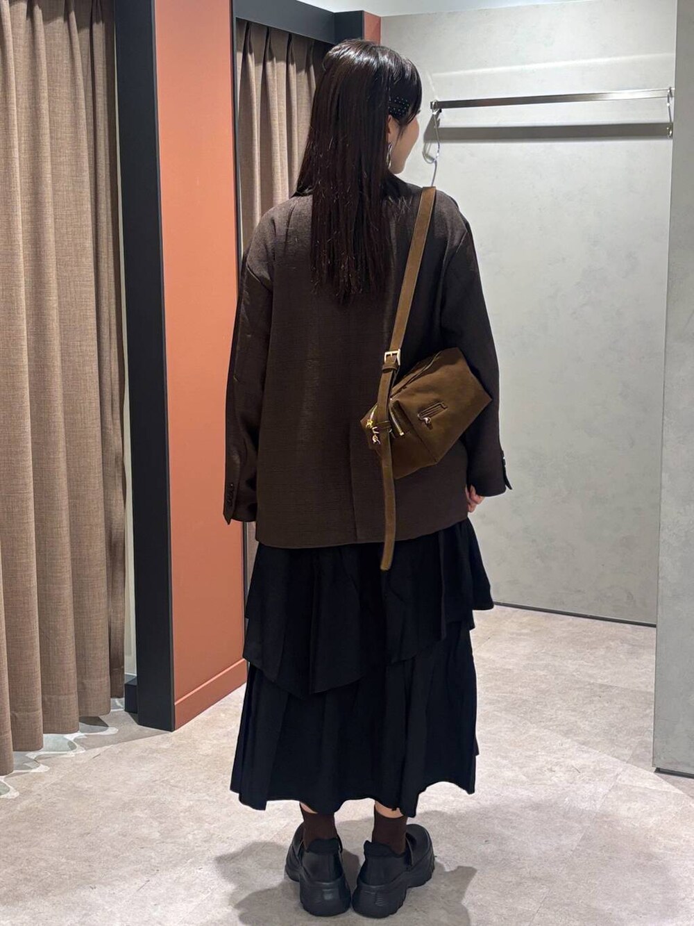 ブラック系のスニーカー、ブラウン系のテーラードジャケット、ブラウン系のショルダーバッグを着用したレディースの秋コーディネートの3枚目の写真