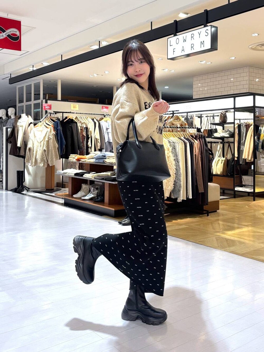 ブラック系のスカート、ブラック系のブーツ、ブラック系のショルダーバッグを着用したレディースの冬コーディネートの4枚目の写真