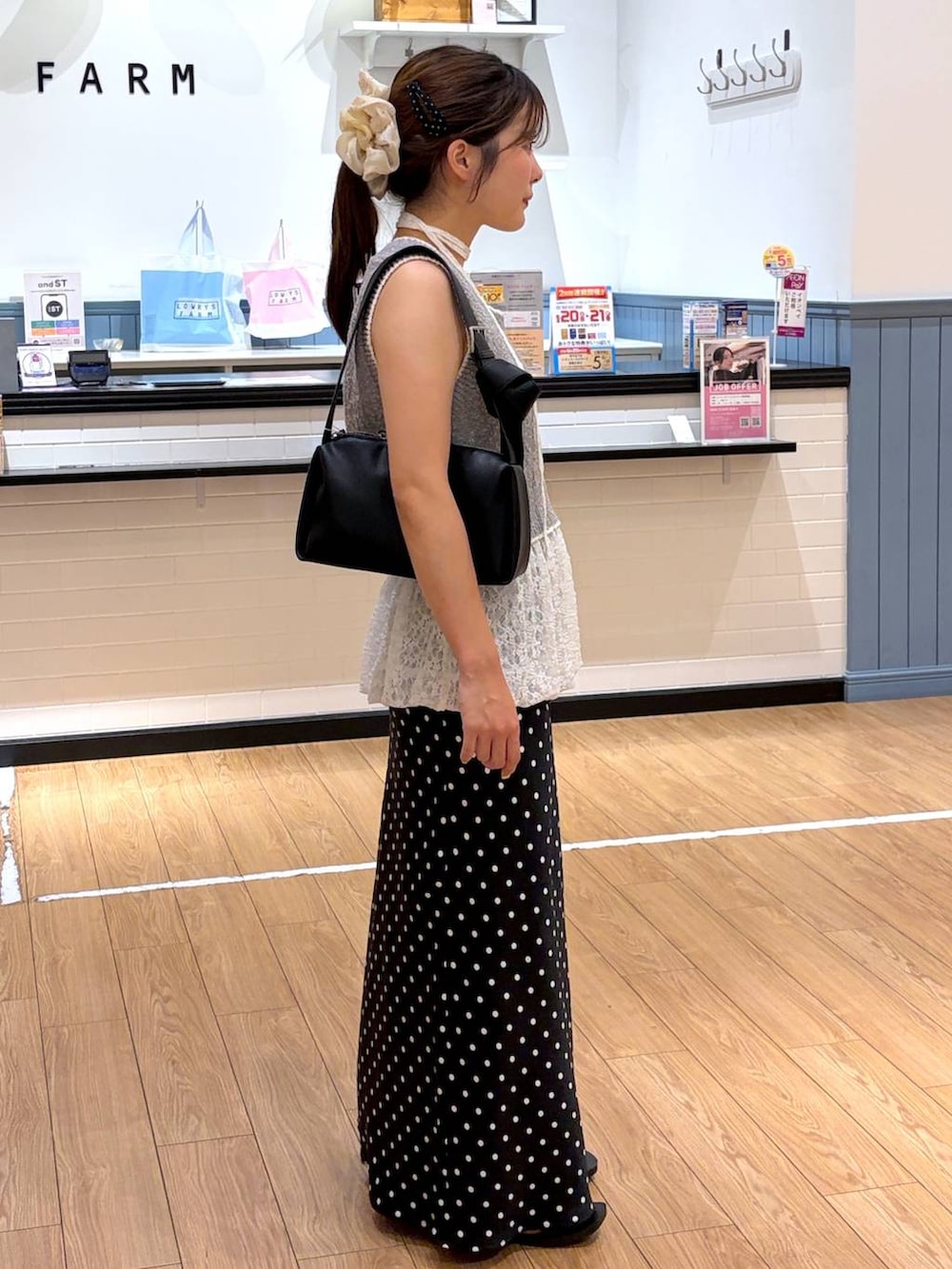 ブラック系のスカート、ブラック系のサンダル、グレー系のベストを着用したレディースの夏コーディネートの2枚目の写真