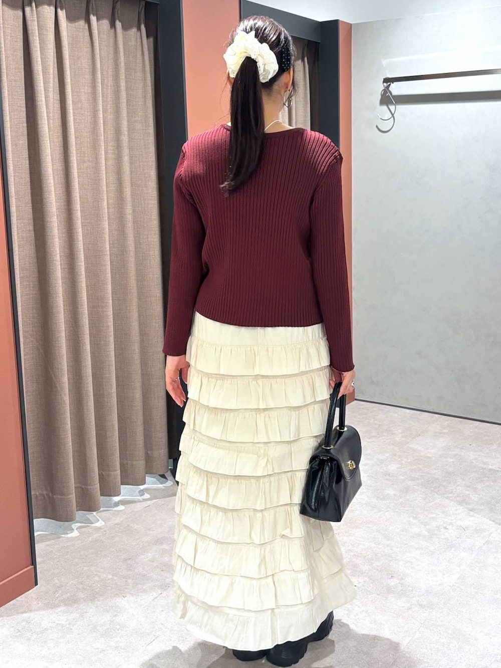 ブラック系のスニーカー、ブラック系のボストンバッグ、ホワイト系のスカートを着用したレディースの秋コーディネートの3枚目の写真