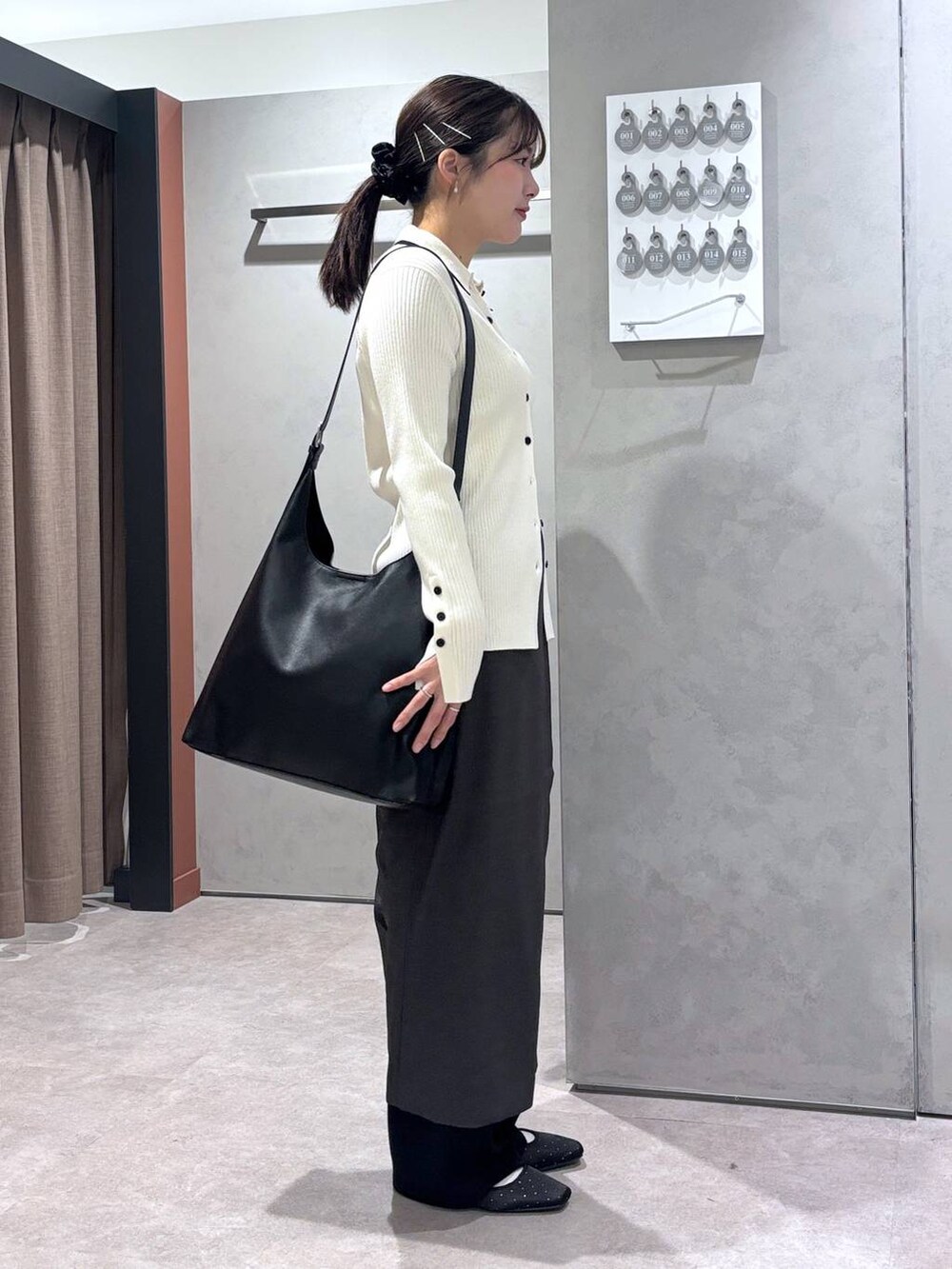 ブラック系のショルダーバッグ、ブラック系のスウェットパンツ、ホワイト系のカーディガン/ボレロを着用したレディースの春コーディネートの2枚目の写真