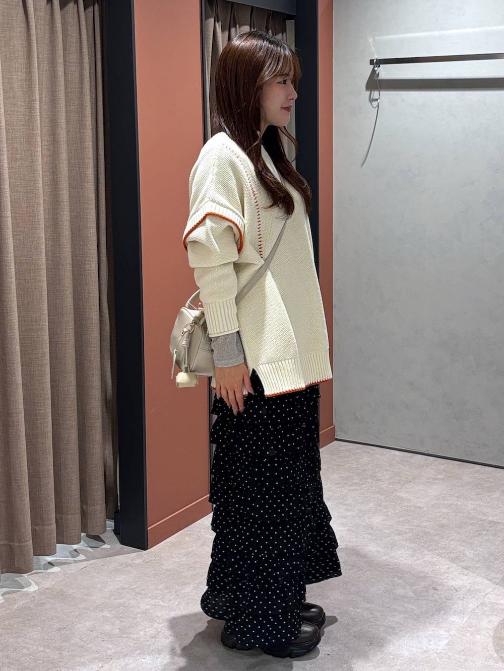 ブラウン系のブーツ、ホワイト系のニット/セーター、その他のスカートを着用したレディースの冬コーディネートの2枚目の写真