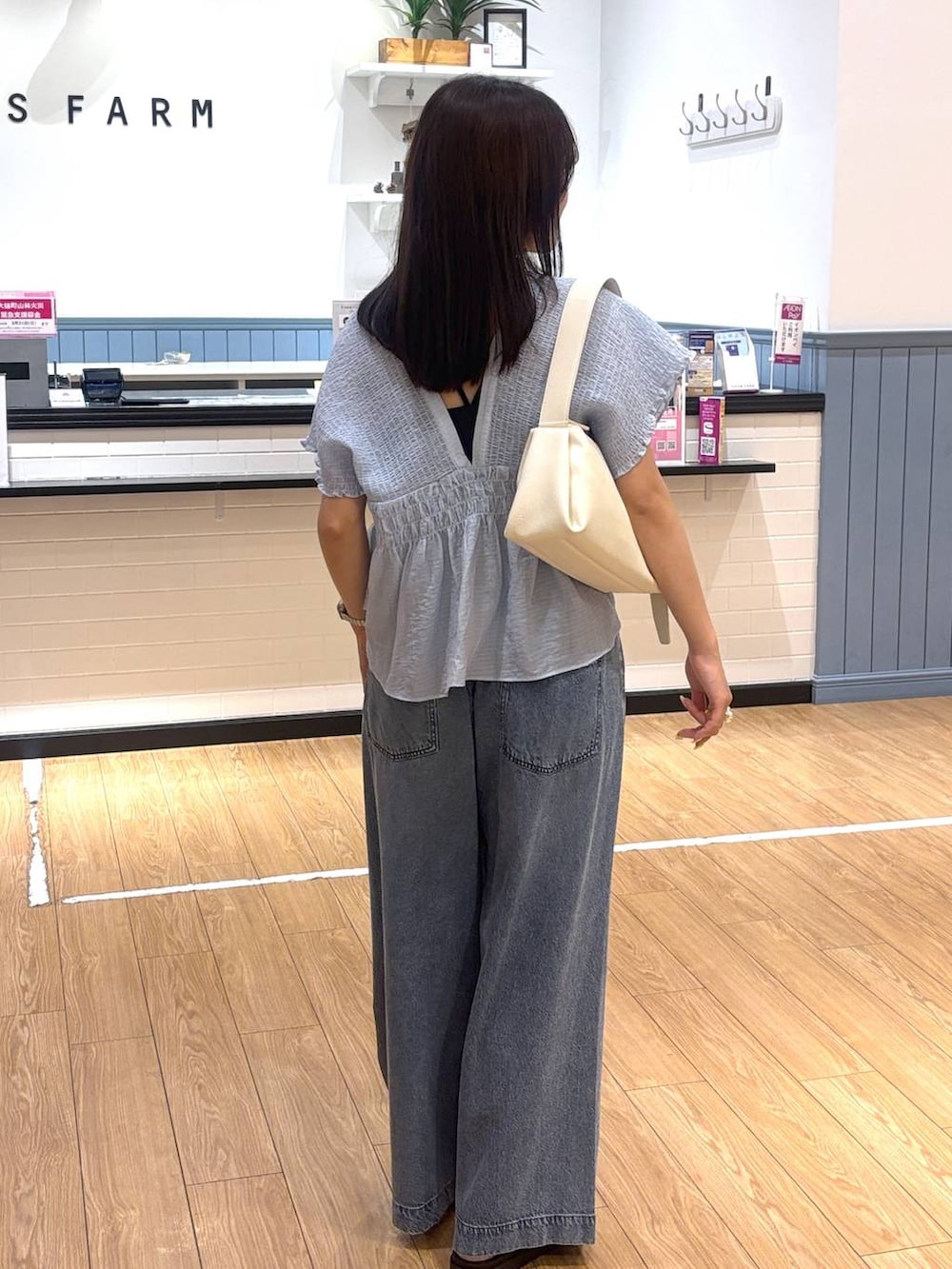 ブルー系のデニムパンツ、ホワイト系のサンダル、ホワイト系のショルダーバッグを着用したレディースの春コーディネートの3枚目の写真