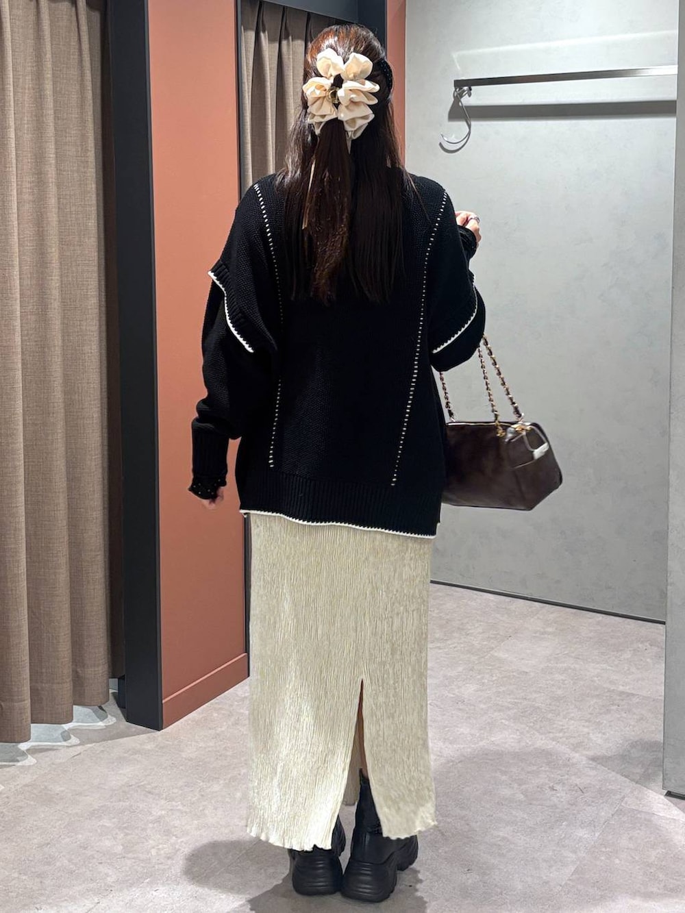 ブラック系のブーツ、ブラック系のニット/セーター、ホワイト系のスカートを着用したレディースの冬コーディネートの3枚目の写真