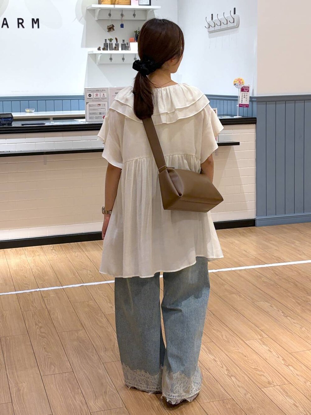 ブルー系のデニムパンツ、ブラウン系のサンダル、ブラウン系のショルダーバッグを着用したレディースの夏コーディネートの2枚目の写真