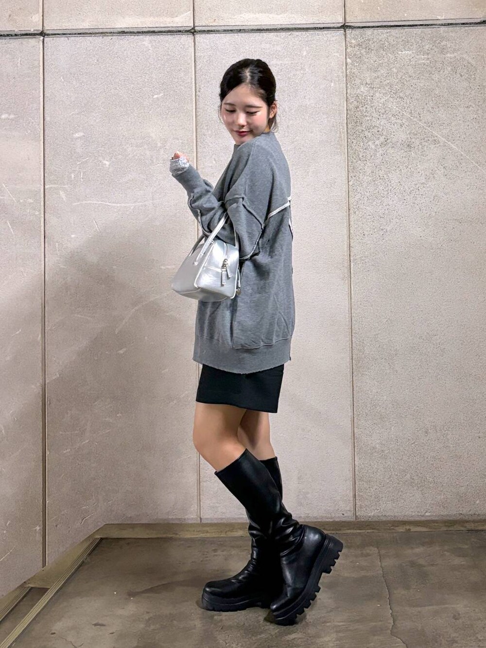 ブラック系のブーツ、シルバー系のボストンバッグ、グレー系のスウェットを着用したレディースの秋コーディネートの2枚目の写真