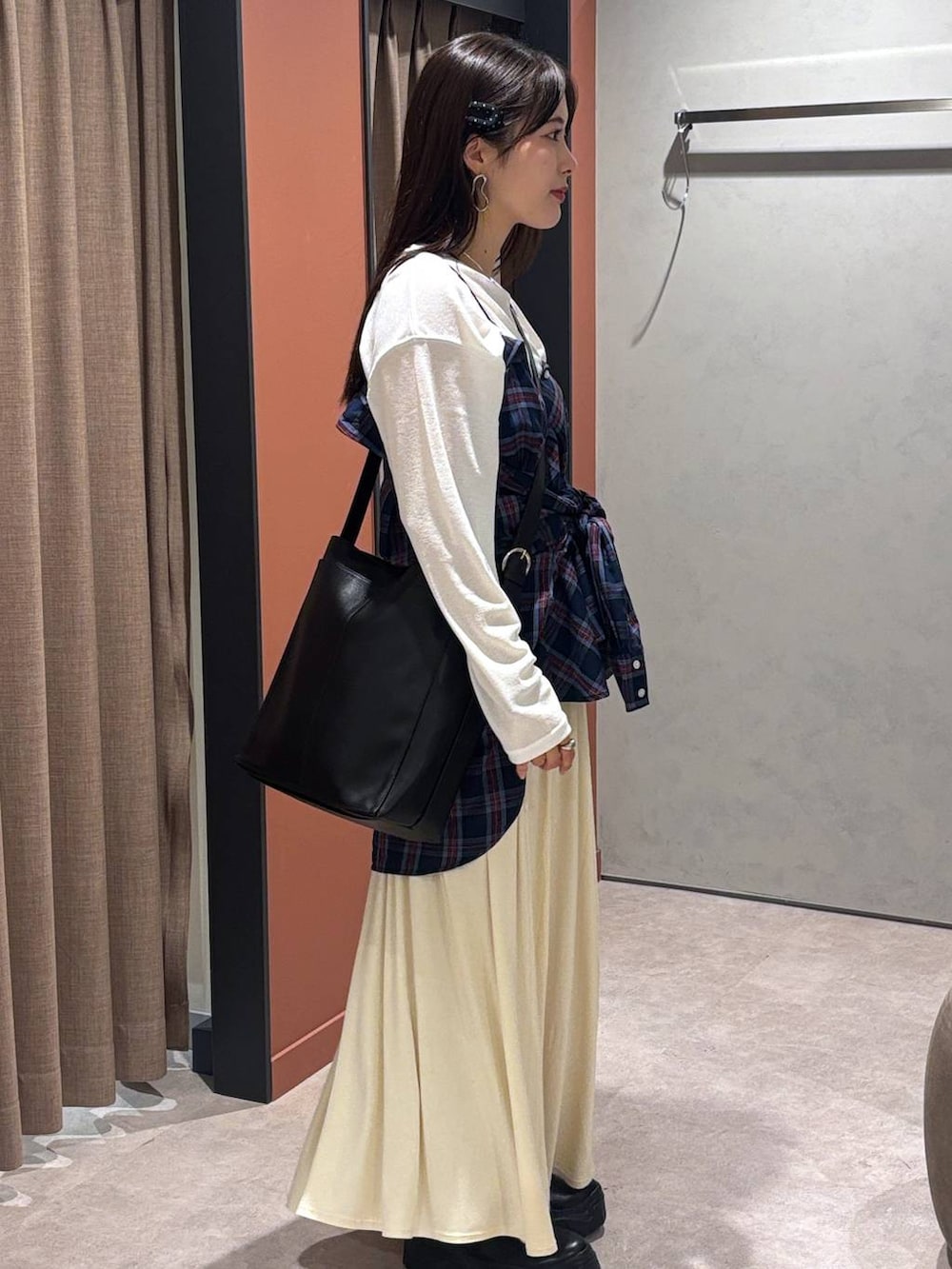 ブラック系のスニーカー、ホワイト系のスカート、ブルー系のシャツ/ブラウスを着用したレディースの秋コーディネートの2枚目の写真