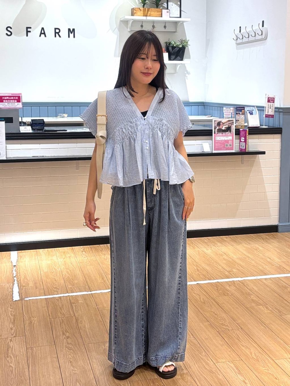 ブルー系のデニムパンツ、ホワイト系のサンダル、ホワイト系のショルダーバッグを着用したレディースの春コーディネートの4枚目の写真