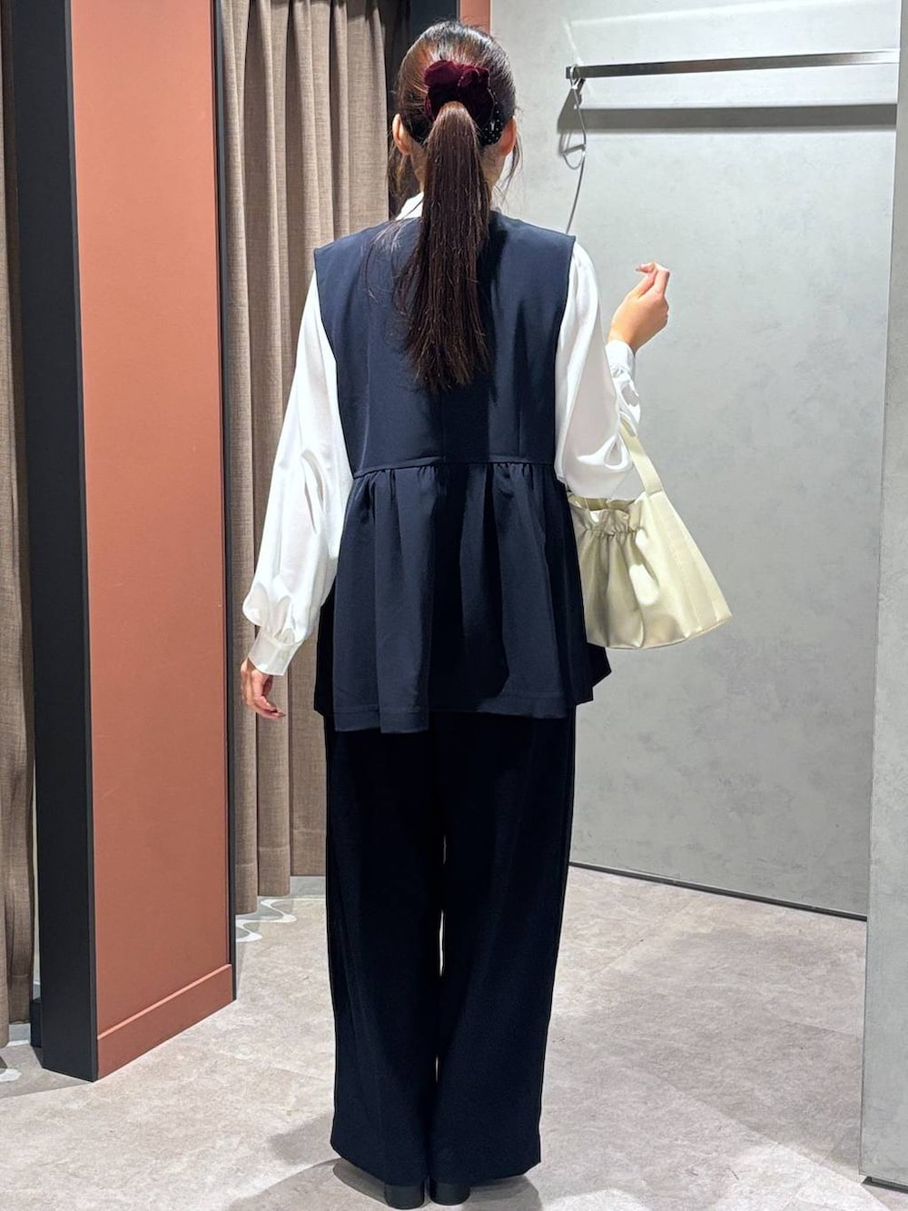 ブラック系のブーツ、ホワイト系のショルダーバッグ、ブルー系のスラックスを着用したレディースの冬コーディネートの3枚目の写真