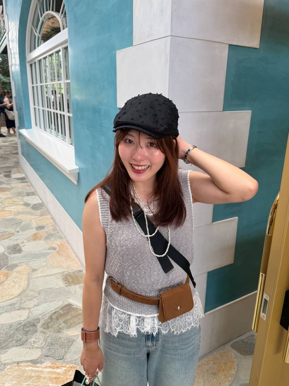 ブルー系のデニムパンツ、ホワイト系のサンダル、グレー系のベストを着用したレディースの夏コーディネートの2枚目の写真