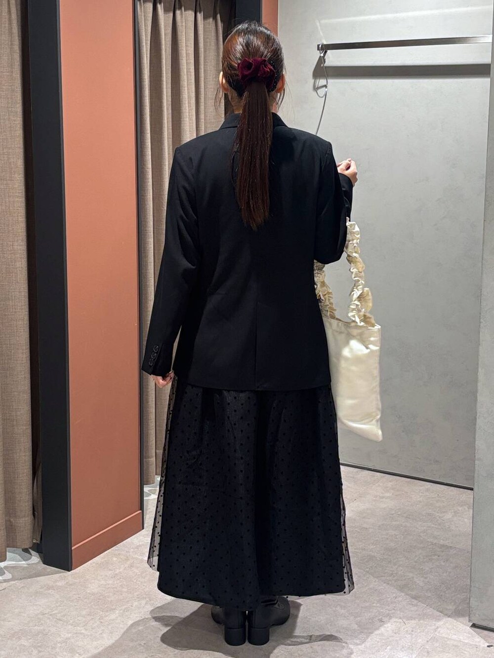 ブラック系のブーツ、ブルー系のテーラードジャケット、ブラック系のスカートを着用したレディースの冬コーディネートの3枚目の写真