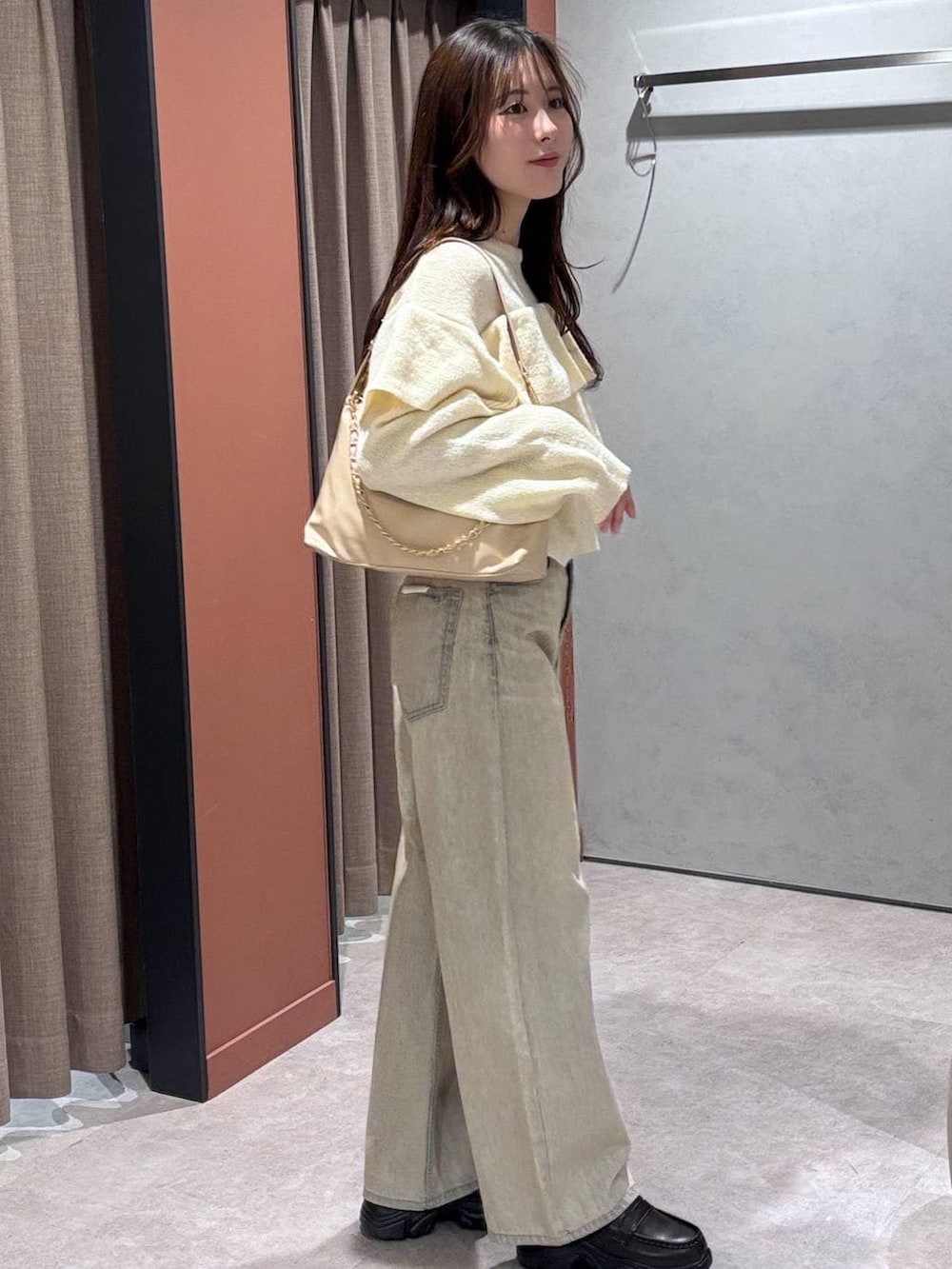 ベージュ系のデニムパンツ、ベージュ系のショルダーバッグ、ブラウン系のローファーを着用したレディースの冬コーディネートの2枚目の写真