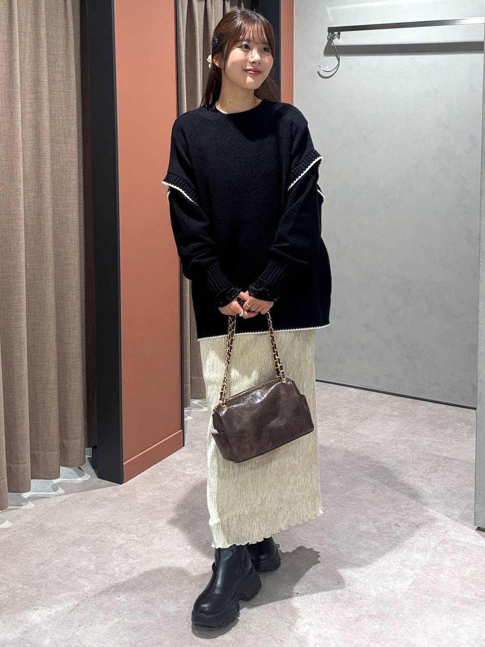 ブラック系のブーツ、ブラック系のニット/セーター、ホワイト系のスカートを着用したレディースの冬コーディネートの4枚目の写真