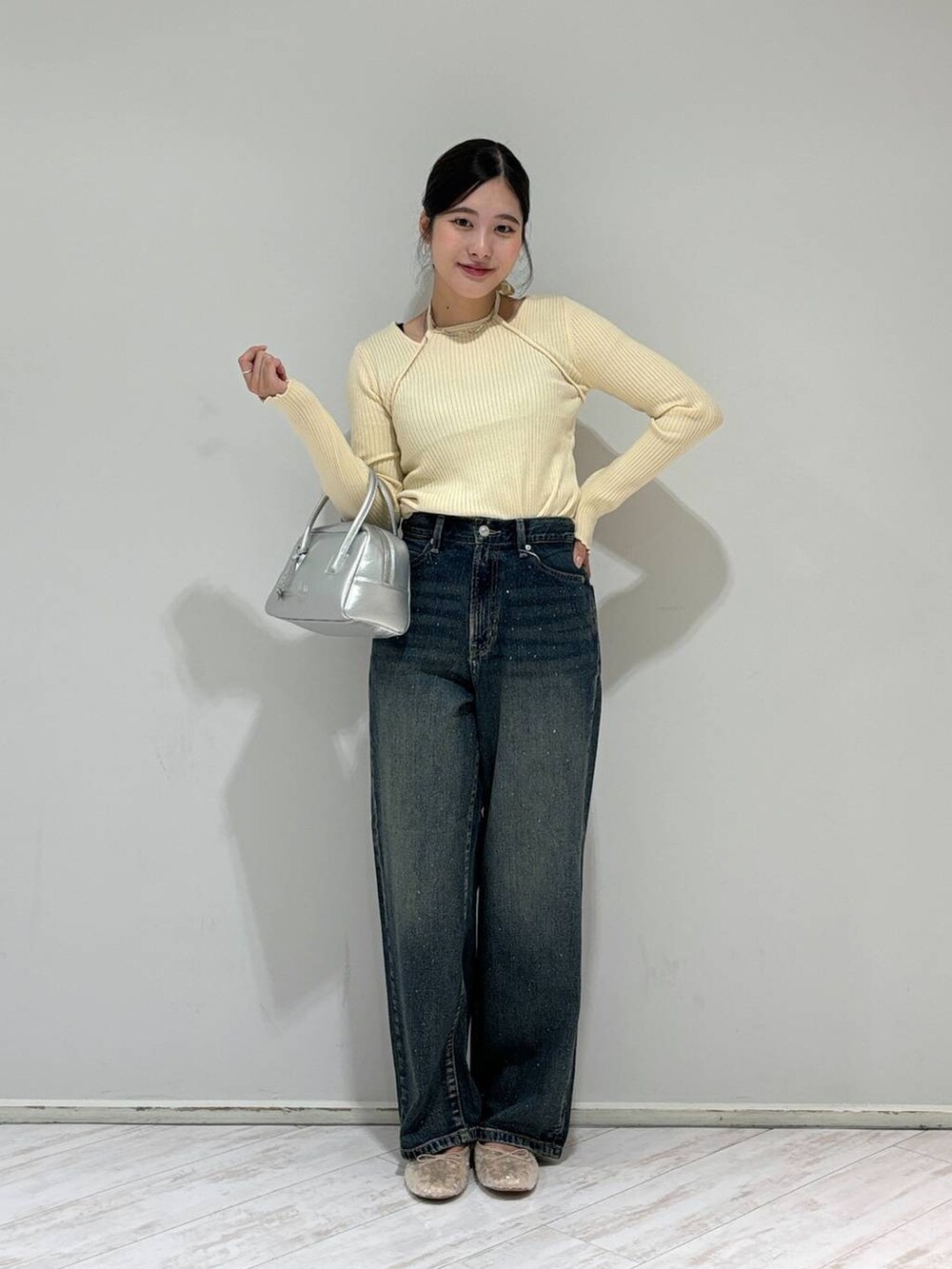 ブルー系のデニムパンツ、シルバー系のボストンバッグ、ホワイト系のバレエシューズを着用したレディースの秋コーディネートの2枚目の写真