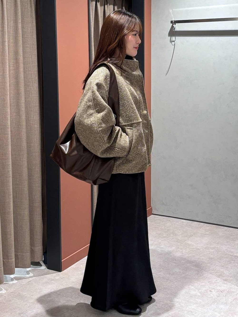 ブラック系のスカート、ベージュ系のブルゾン、ブラック系のブーツを着用したレディースの冬コーディネートの2枚目の写真