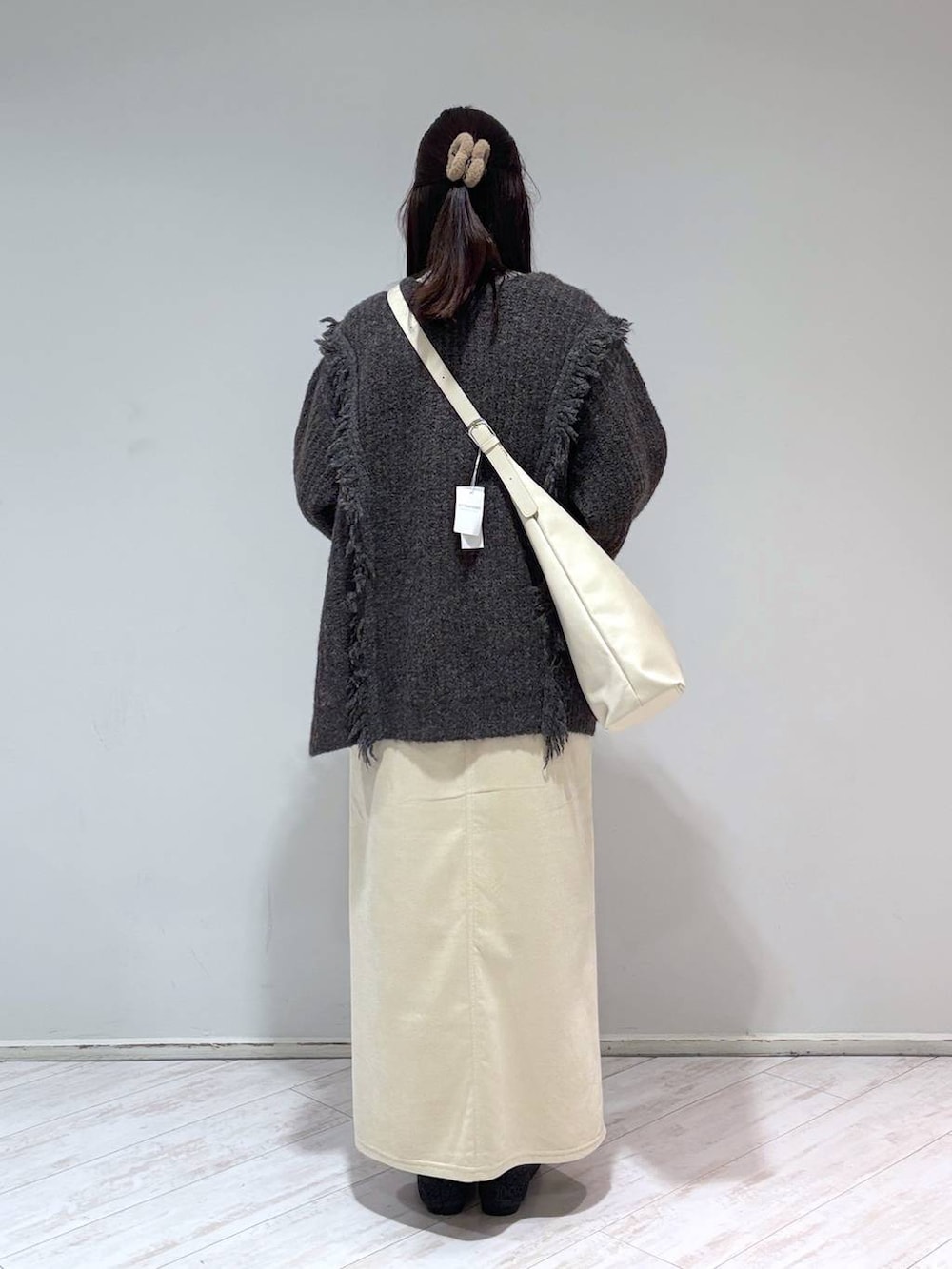 ホワイト系のショルダーバッグ、シルバー系のTシャツ/カットソー、グレー系のニット/セーターを着用したレディースの冬コーディネートの3枚目の写真