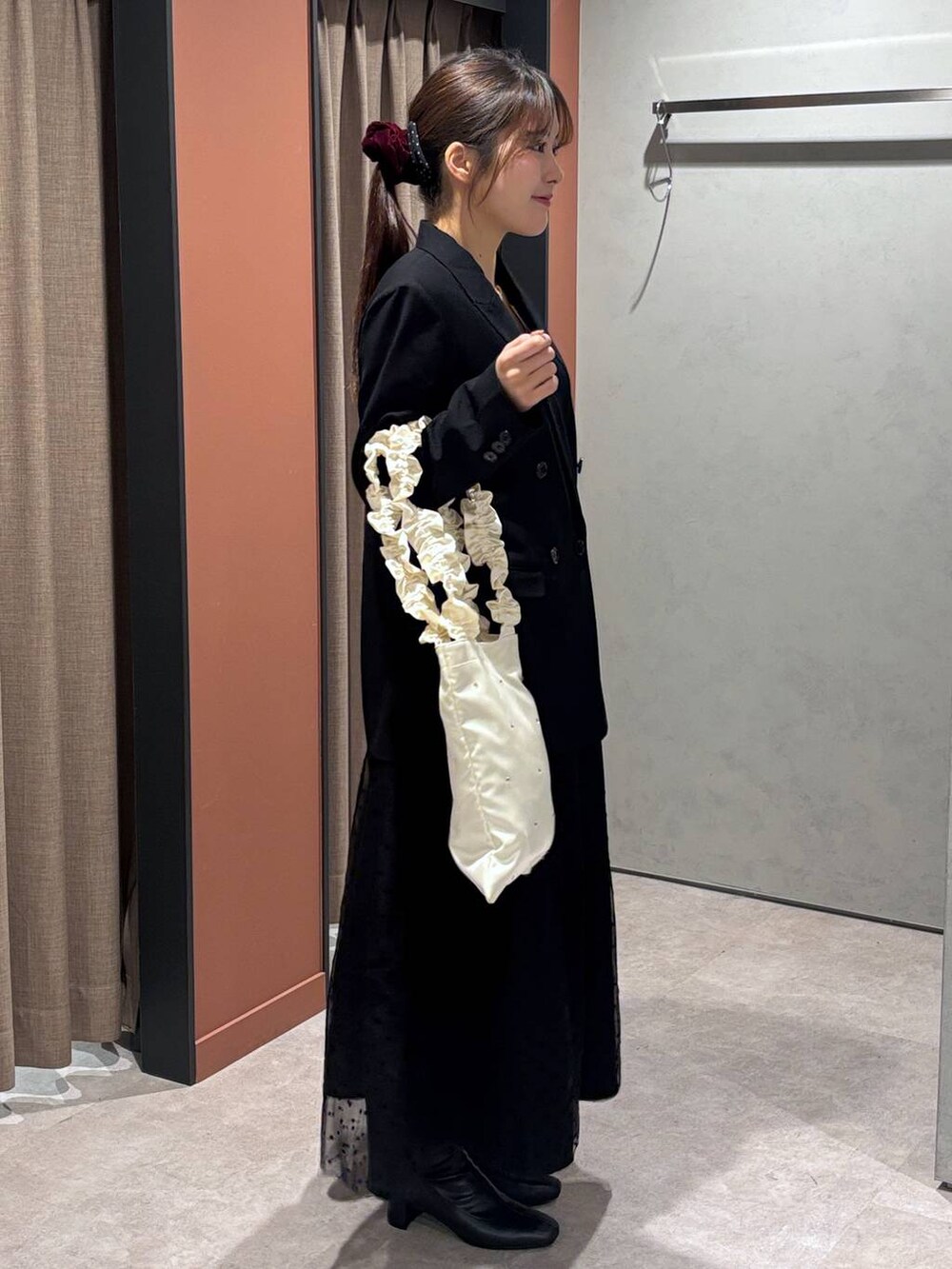 ブラック系のブーツ、ブルー系のテーラードジャケット、ブラック系のスカートを着用したレディースの冬コーディネートの2枚目の写真