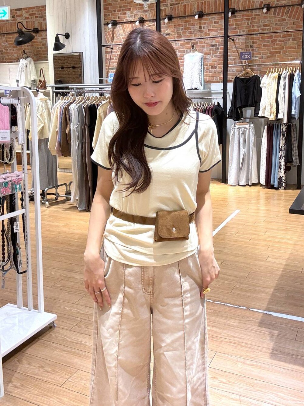 オレンジ系のデニムパンツ、ブラック系のサンダル、イエロー系のベルトを着用したレディースの春コーディネートの2枚目の写真