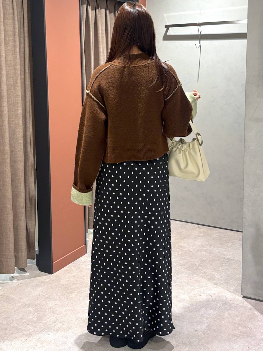 ブラック系のスカート、ブラック系のサンダル、ホワイト系のショルダーバッグを着用したレディースの冬コーディネートの3枚目の写真