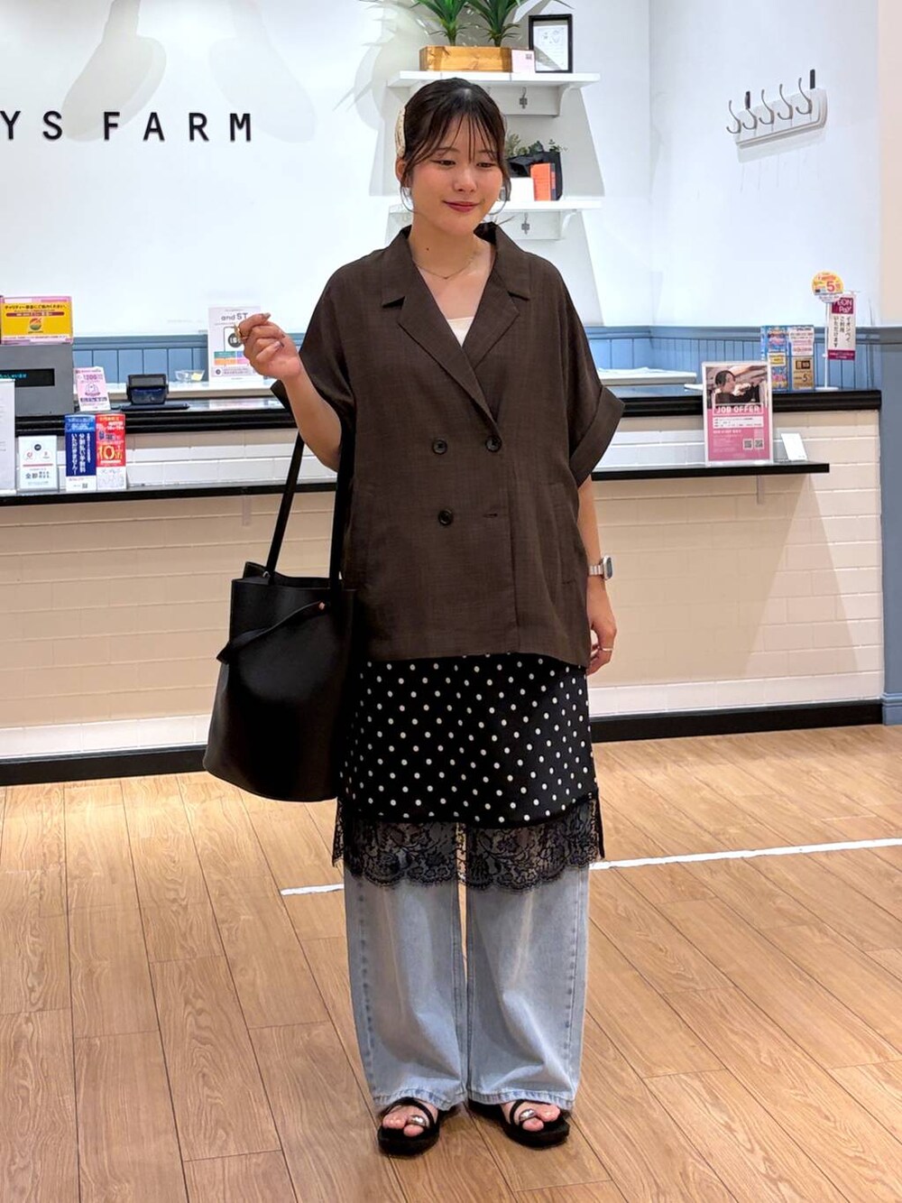 ブルー系のデニムパンツ、ブラウン系のテーラードジャケット、ブラック系のサンダルを着用したレディースの夏コーディネートの4枚目の写真
