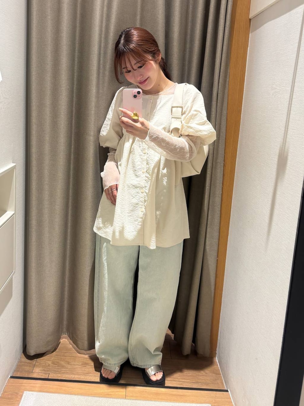 ブルー系のデニムパンツ、シルバー系のサンダル、ホワイト系のショルダーバッグを着用したレディースの春コーディネートの2枚目の写真