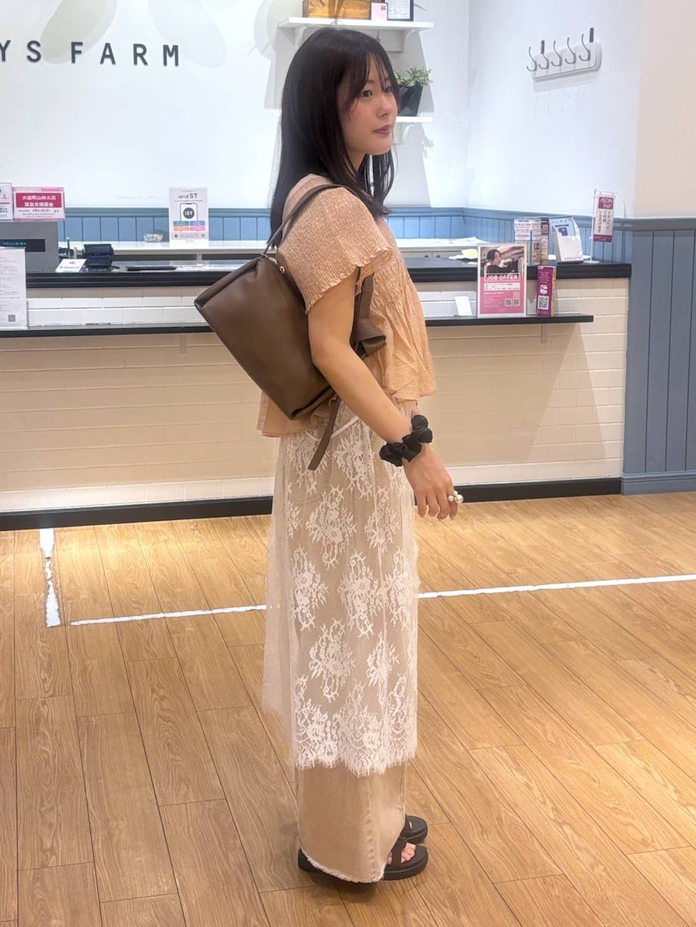 オレンジ系のデニムパンツ、ブラウン系のサンダル、ブラウン系のショルダーバッグを着用したレディースの春コーディネートの2枚目の写真