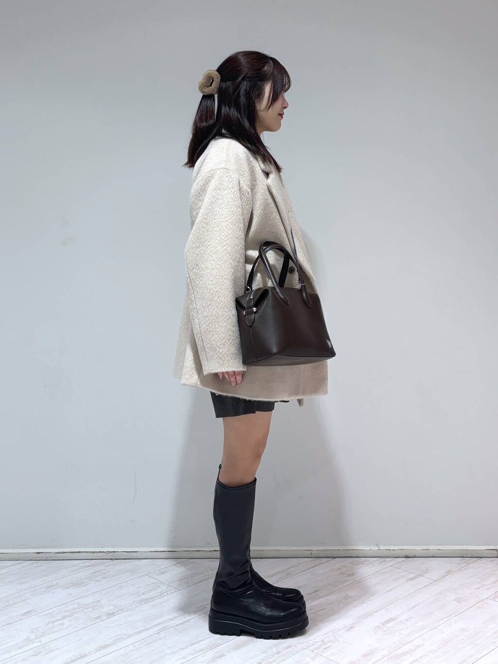 ブラック系のブーツ、ブラウン系のショルダーバッグ、ベージュ系のその他アウターを着用したレディースの冬コーディネートの2枚目の写真