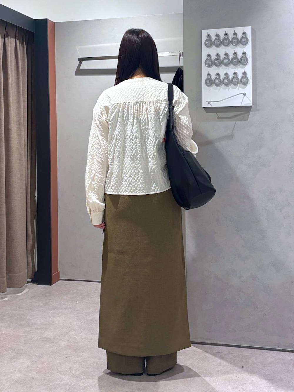 ブラウン系のスラックス、ブラウン系のスカート、ブラック系のトートバッグを着用したレディースの春コーディネートの3枚目の写真